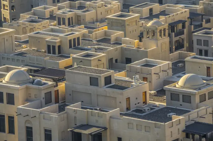 Elegant adobe-style homes beneath the towering gaze of the nearby Burj Khalifa in Dubai.