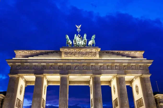 The iconic landmark of the Brandenburger Tor floodlit at twilight in Berlin.