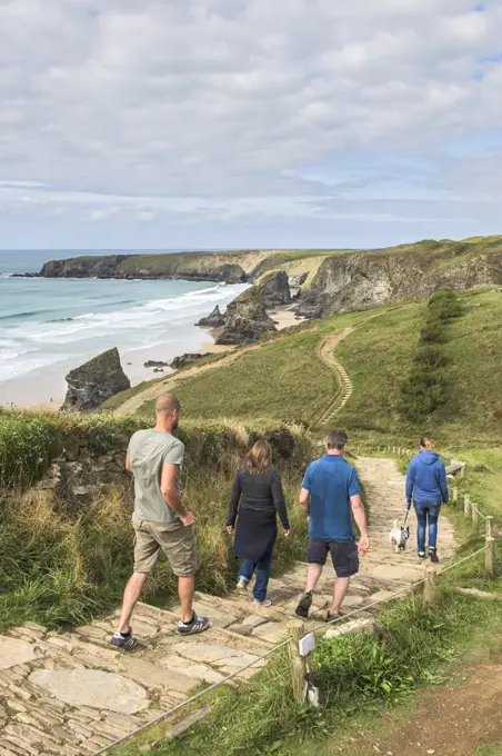 Tourists walk along the South West Coastal Path towards Bedruthan Steps in Cornwall.