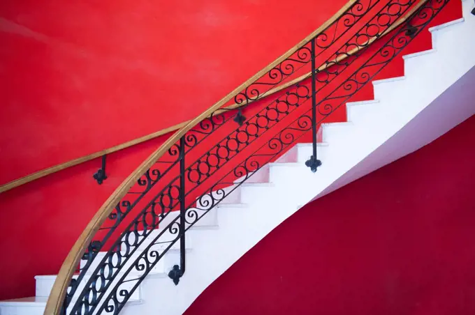 White sweeping staircase set against a red wall in Havana.