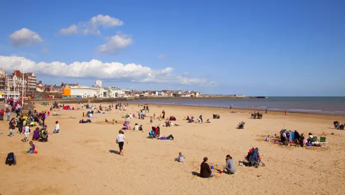 England, East Riding of Yorkshire, Bridlington. Holidaymakers enjoying the sun on Bridlington's South Beach with the Spa in the background.