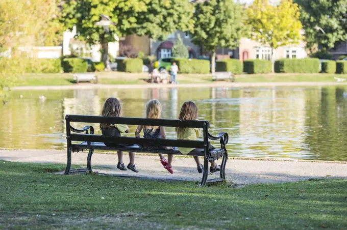 Three children sat together on a park bench in Memorial park in Herne Bay.