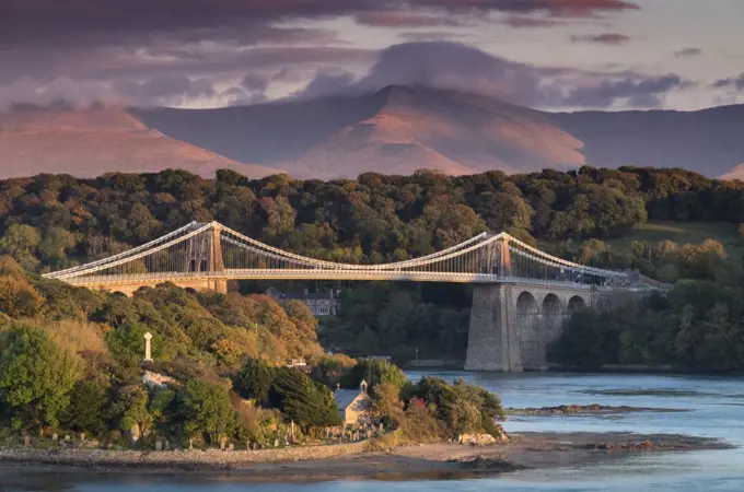 Menai Bridge over the Menai Strait backed by the mountains of Snowdonia in North Wales.