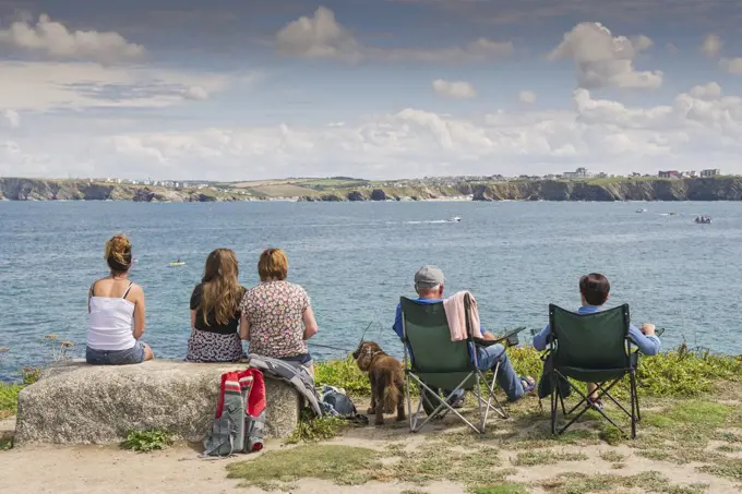 Holidaymakers sit and relax as they look out over the sea at Newquay in Cornwall.