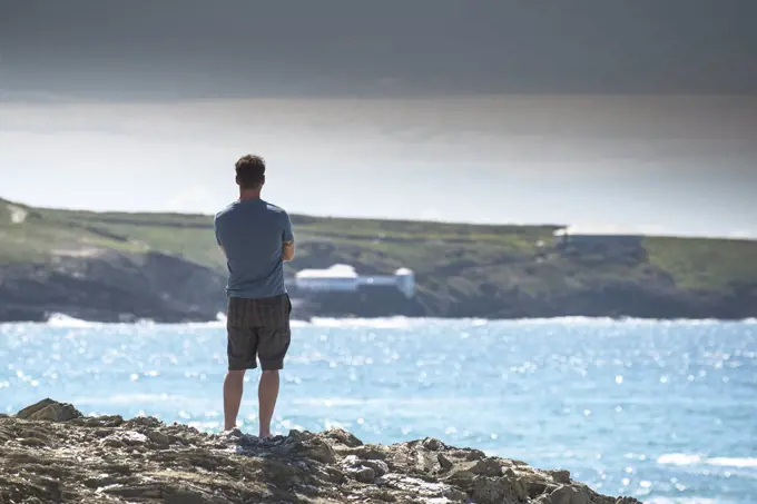 A holidaymaker stands on The Headland in Newquay looking out to sea.