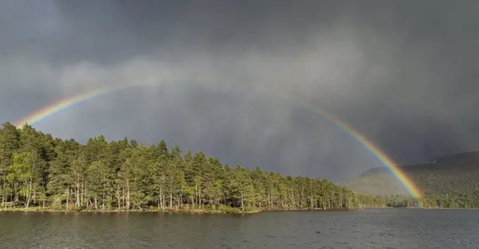 Rainbow and storm cloud over Loch an Eilein in the Cairngorms in Scotland.