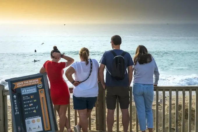 Holidaymakers standing looking out over Fistral Beach in Newquay in Cornwall.