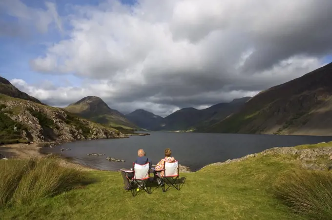 England, Cumbria, Wast Water. A couple enjoy the view over Wast Water. Wast Water is the deepest and coldest lake in the UK. In the centre is The Great Gable 2949 feet.