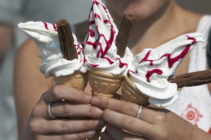 England, Lancashire, Morecambe. A close up of a woman holding three ice cream cones on the sea front at Morecambe.