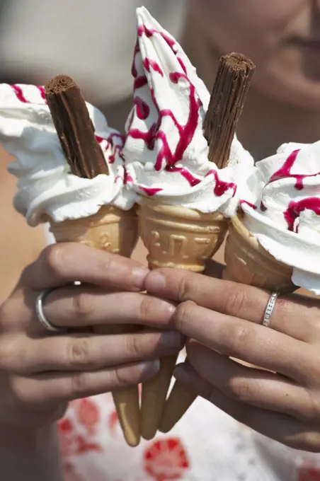 England, Lancashire, Morecambe. A close up of a woman holding three ice cream cones on the sea front at Morecambe.