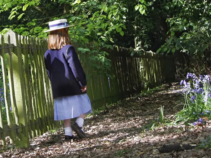 England, London, Holland Park. A young girl wearing school uniform walking through autumnal leaves in Holland Park.