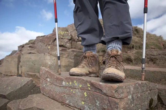 England, Powys, Pen Y Fan. Close-up of a walkers boots and poles standing on Pen Y Fan Mountain, the highest peak in South Wales.