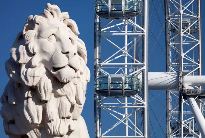 England, London, South Bank. Coade stone lion at the end of Westminster Bridge with London Eye in the background.