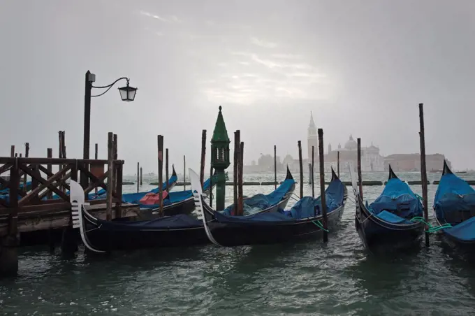 Italy, Venetto, Venice. Gondolas moored in the Lagoon on a misty morning in Venice.