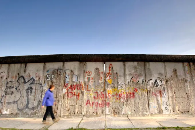 Germany, Berlin, East Side Gallery. A man walks past the Berlin Wall along Bernauer Strasse in East Berlin.