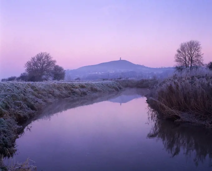 England, Somerset, Glastonbury. The River Brue on South Moor on the Somerset Levels at Glastonbury with Glastonbury Tor in the distance, Somerset.