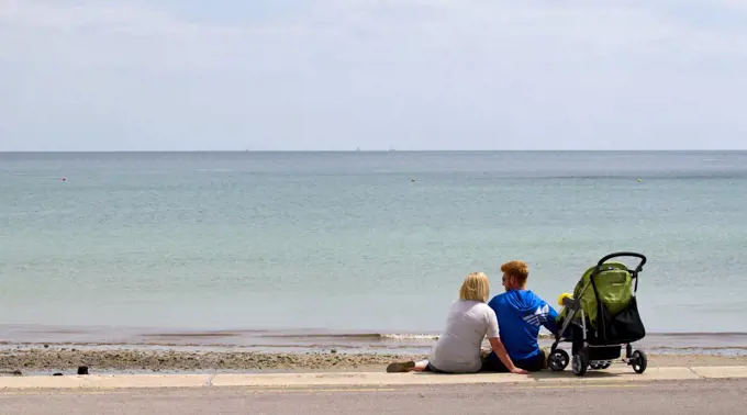 England, West Sussex, Bognor Regis. A young family sitting together on the seafront at Bognor Regis.