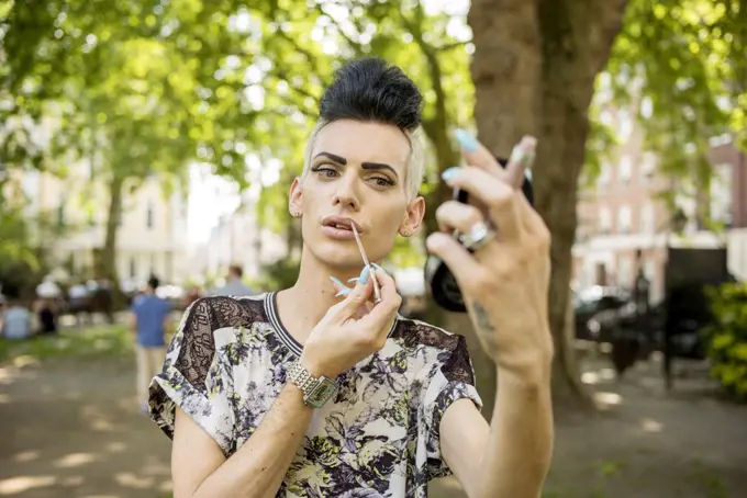 A gay man applies his make up.