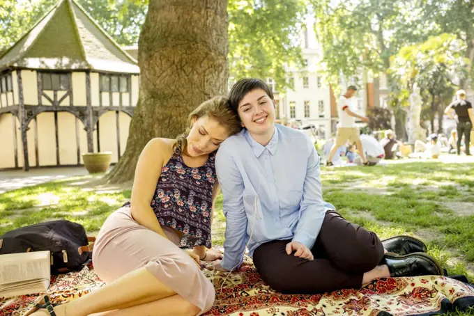 A young lesbian couple enjoy the sunshine in the park.