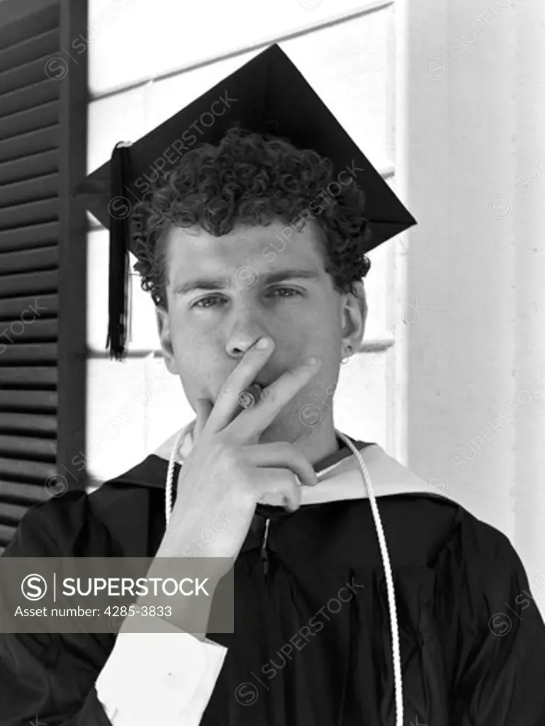 Young man smoking a cigar on the front porch after graduation. MR