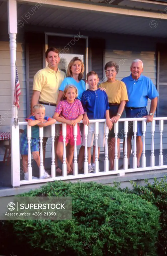 Family with grandparents pose on house porch