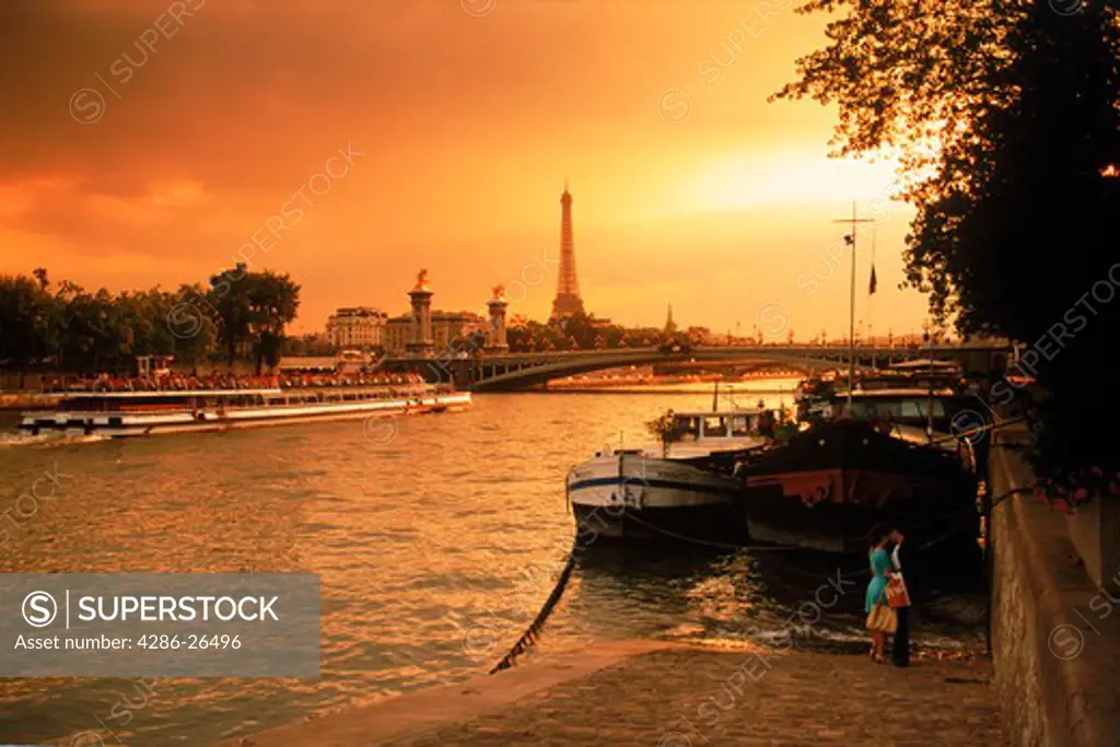 Couple on Seine River in Paris at sunset with Eiffel Tower beyond