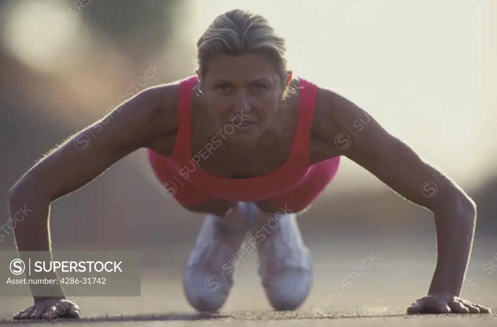 Woman doing push-ups outdoors.