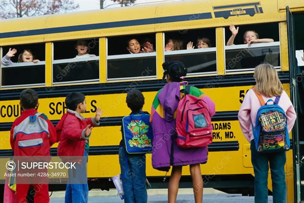 Elementary school students getting on bus.  (model released)