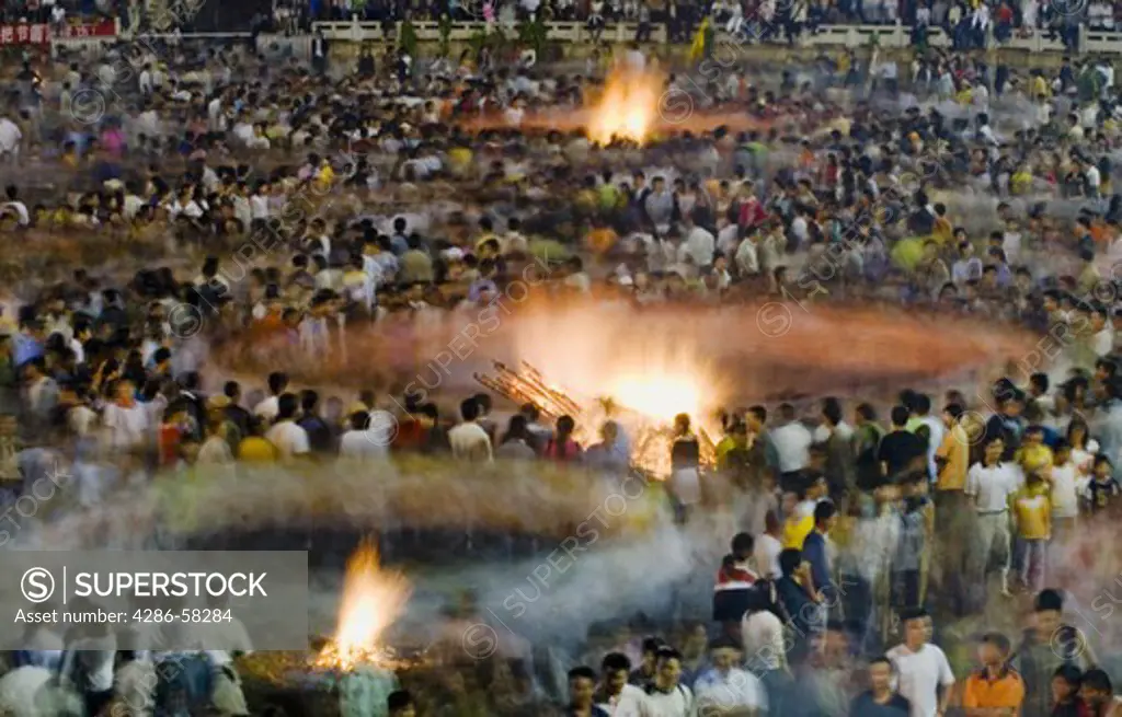 Creating solar systems of movement, audience members dance around bonfires at annual June Torch Festival, commemorating story of Sani ethnic minority saving crops from locusts with buring torches, Shilin, Yunnan Province, China.