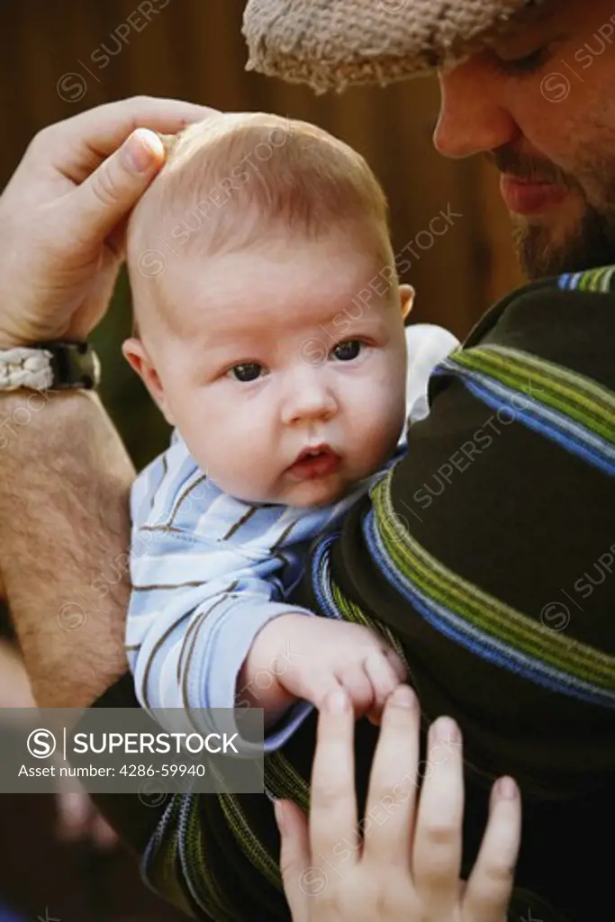 Side profile of a young man carrying his baby