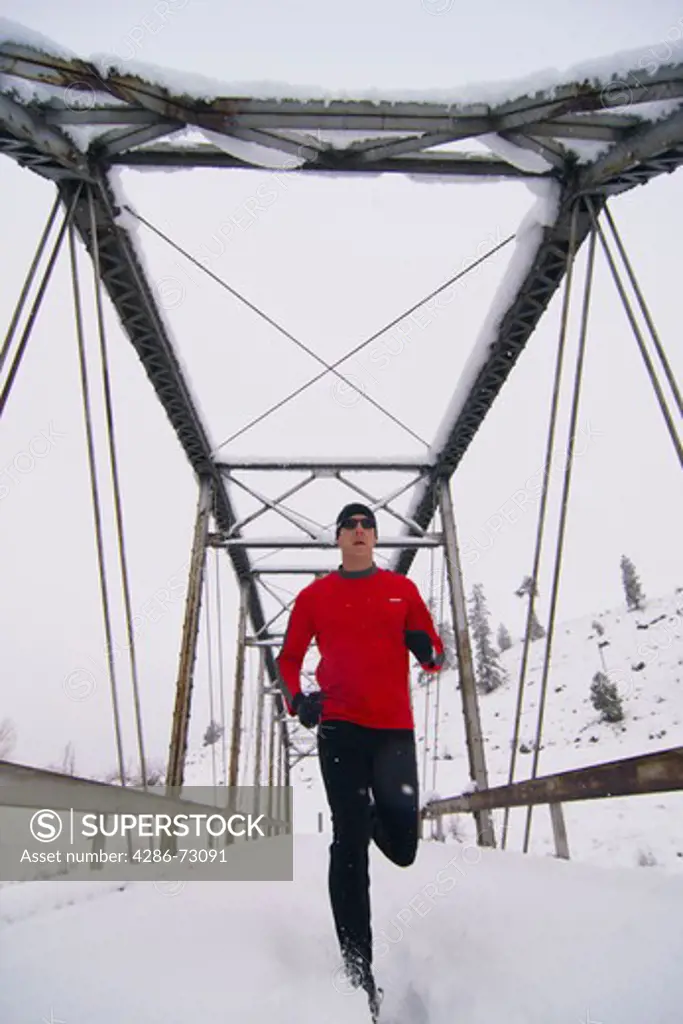 A man running across a trestle brigde on a snowy day near Truckee in California