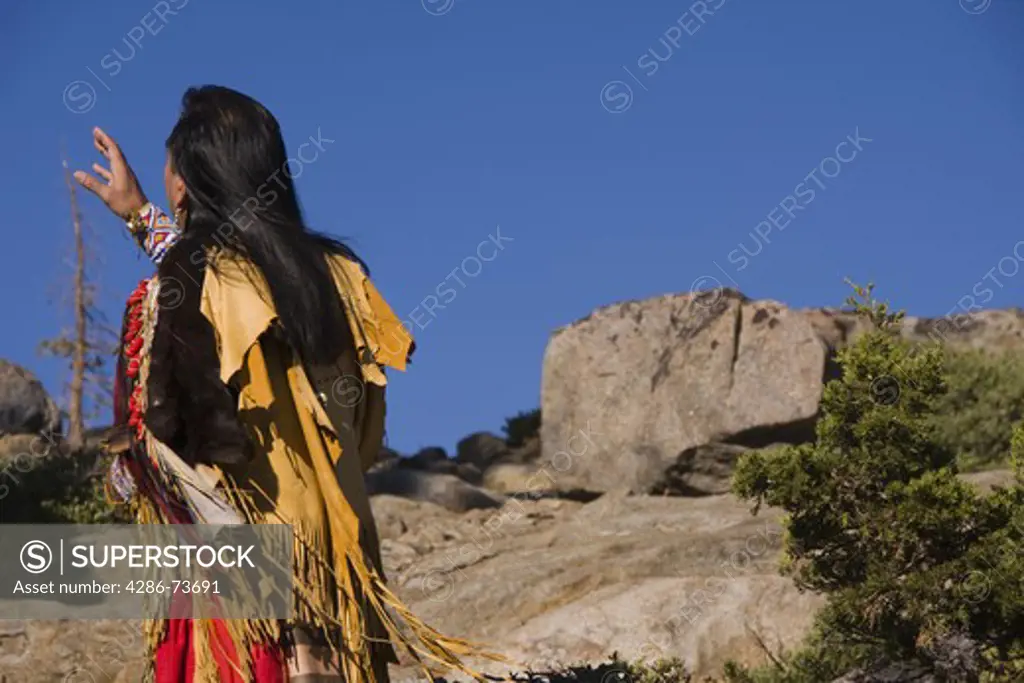 A Lakota Native American Indian warrior in full traditional dress standing outdoors on a rock reciting a poem on Donner Summit near Truckee in California