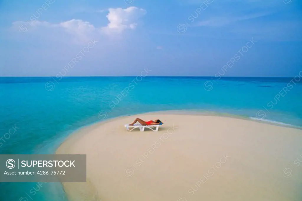 Woman relaxing alone on beach chair on sandbar in Maldive Islands