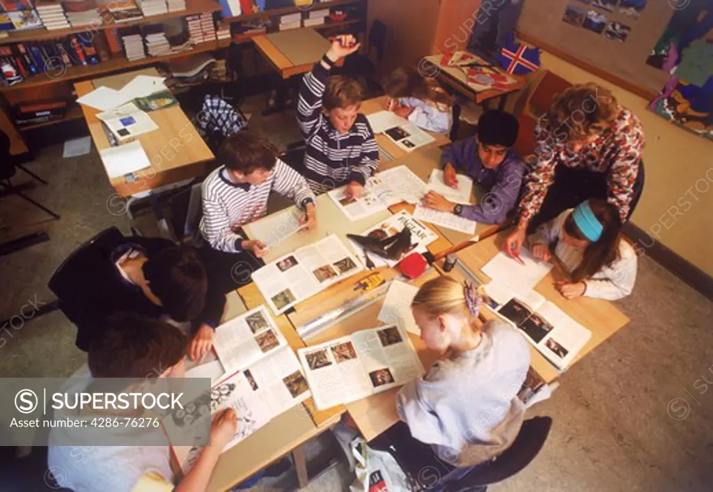 Elementary school children reading and writing with teacher in Swedish classroom