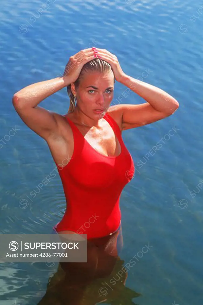 Blond woman of Brazilian Swedish ethnicity bathing in lake in red swimsuit