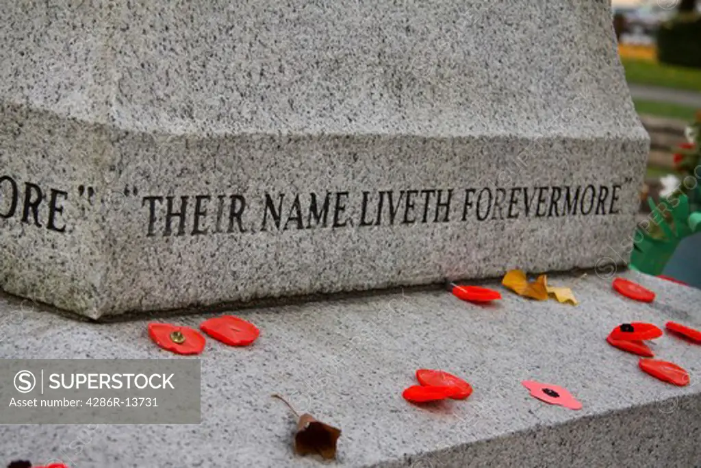 Cenotaph with red poppies on Remembrance Day. Words - Their name liverth forevermore