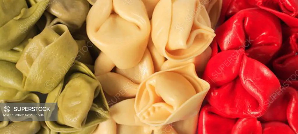 Coloured tortellini pasta shells arranged in the form of an Italian flag.