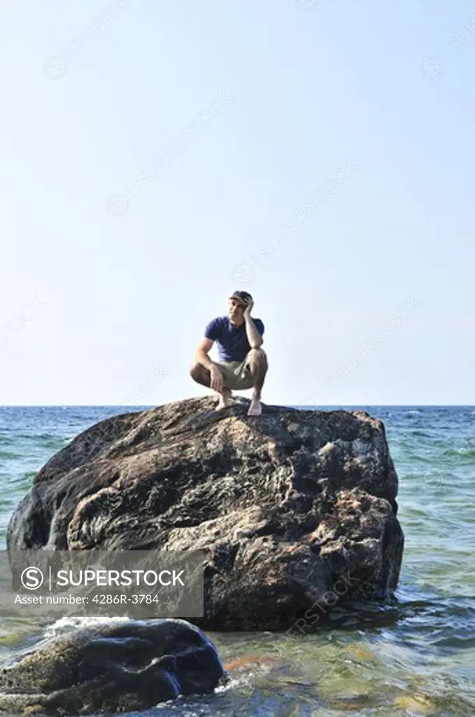 Man stranded on a rock in ocean waiting for rescue