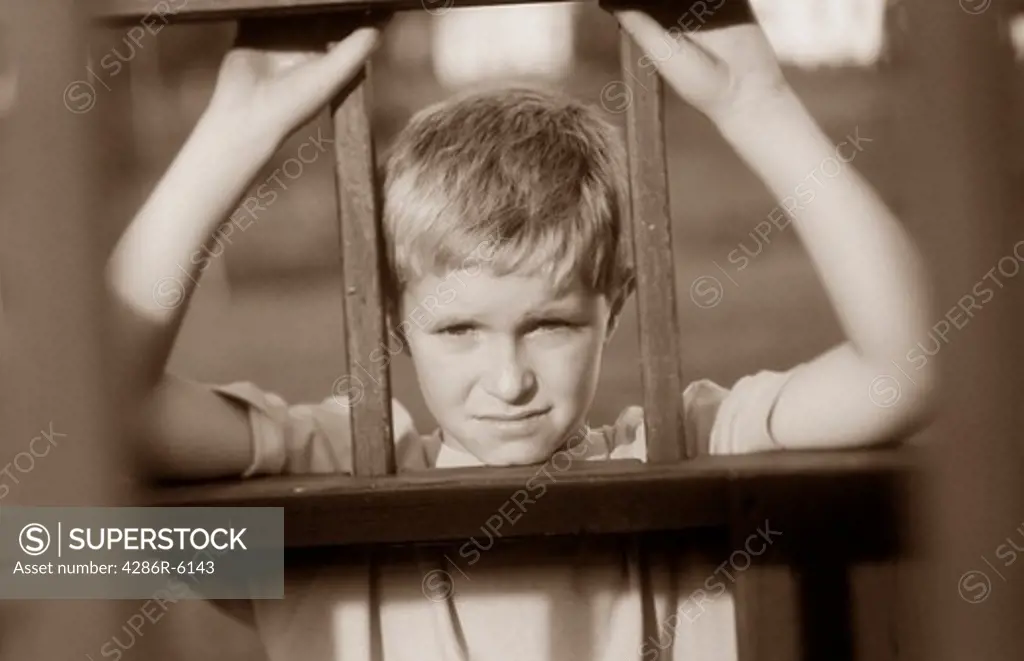 Sad young caucasian male leaning against wrought iron fence