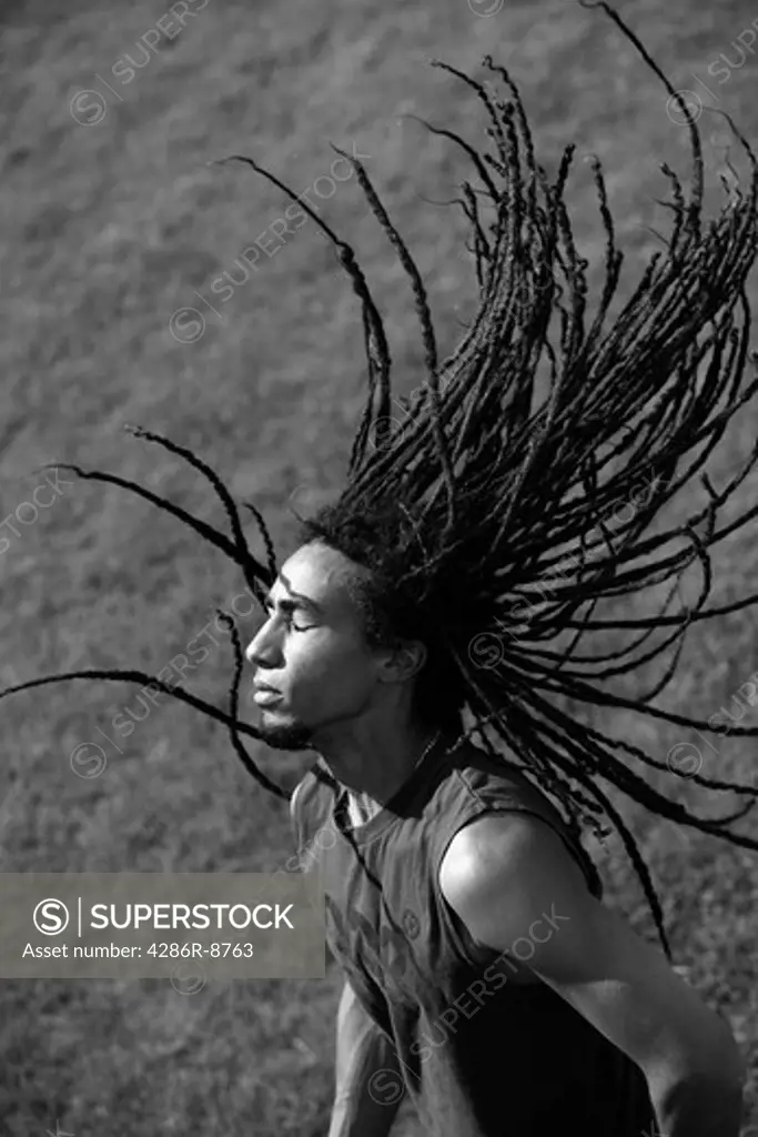 Man dancing with dreadlocks flying in the air