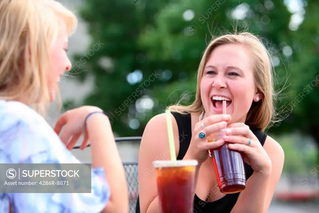 Girlfriends sitting together at an outdoor cafe talking