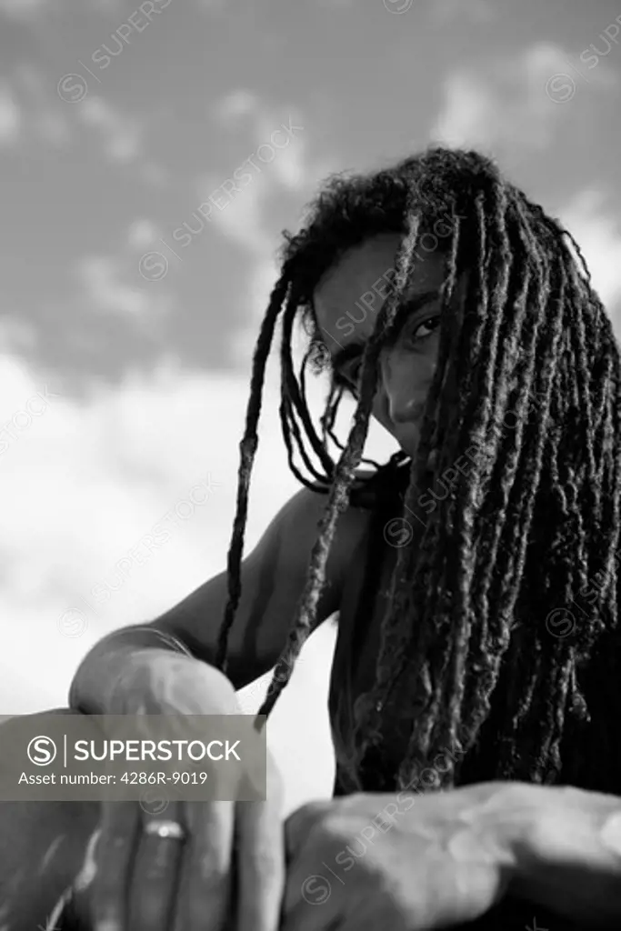 Man with dreadlocks covering face