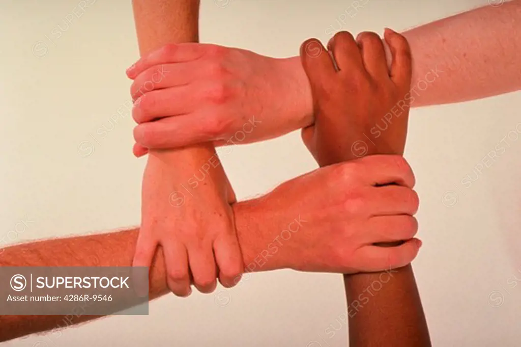 Four multi-racial hands clasping in an interlocking formation.