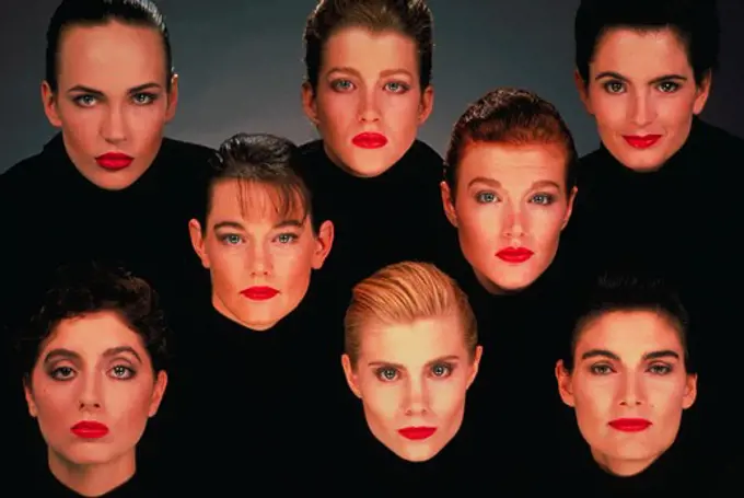 Portrait of eight women draped in black wearing red lipstick with a gray background.