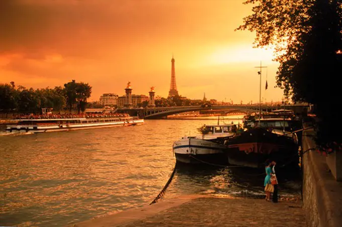 Couple on Seine River in Paris at sunset with Eiffel Tower beyond