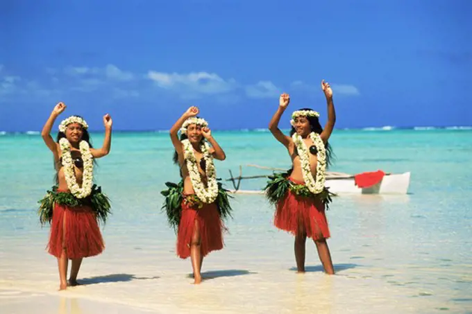 Three Polynesian girls with outrigger in Aitutaki lagoon