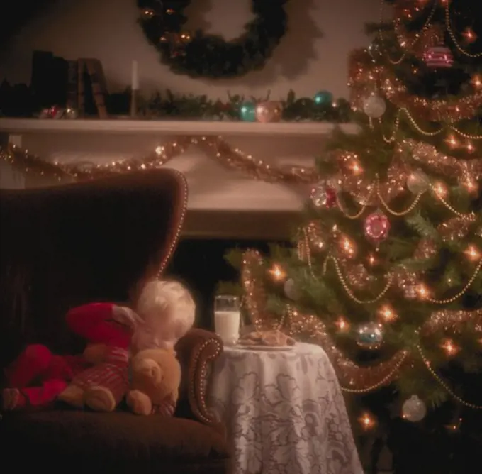 Young boy sleeping next to Christmas tree waiting for Santa Claus.