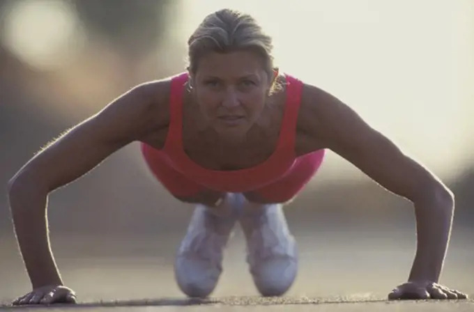 Woman doing push-ups outdoors.