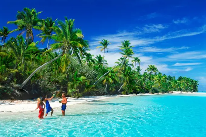 Tourists drinking from coconuts off One Foot Island in Aitutaki lagoon in Cook Islands