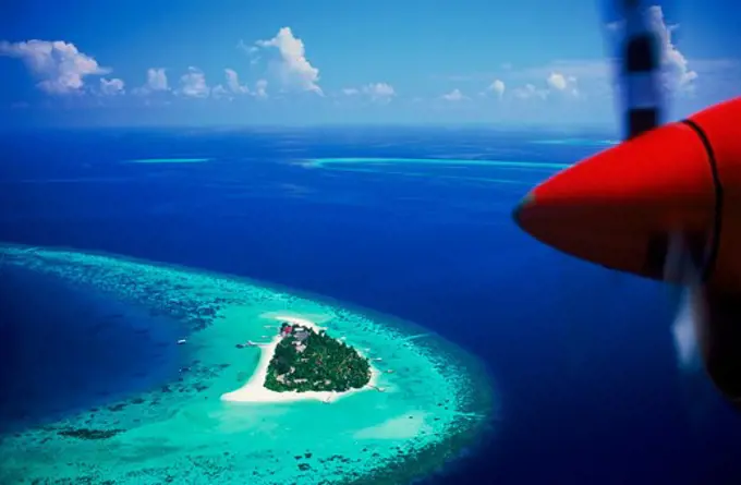 Aerial view with plane prop over Mayafushi Island in Maldive Islands amid blue Indian Ocean waters of North East Ari Atoll